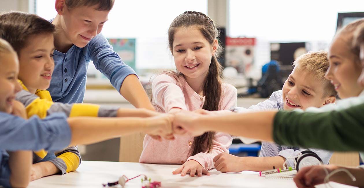 Group of kids building robots bumping fists